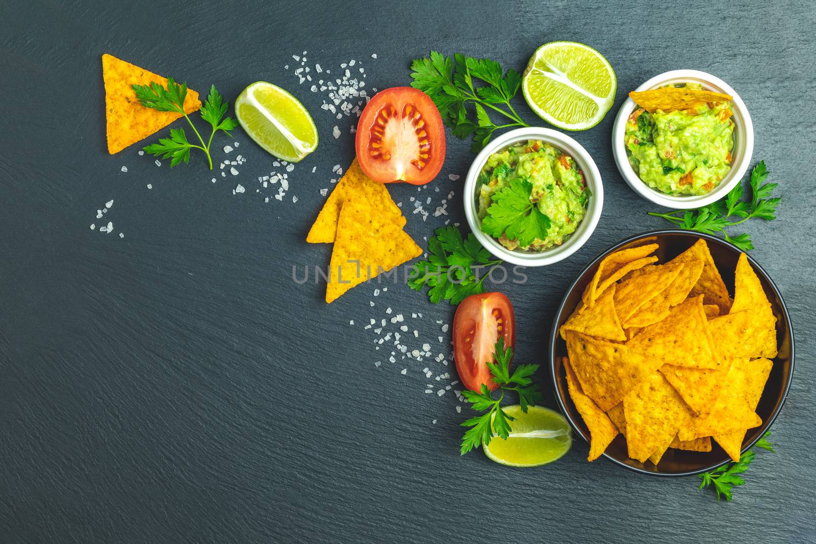 Guacamole and nachos with ingredients on the background of a bla by ArtSvitlyna