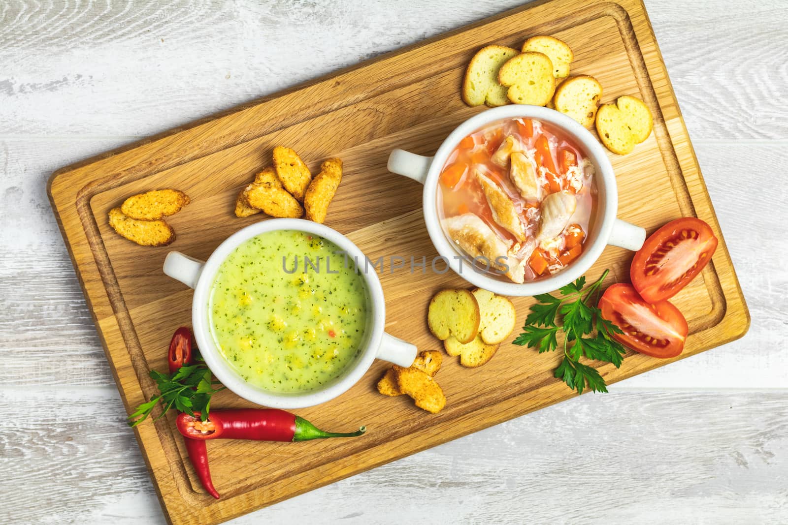 Concept of healthy vegetable and legume soups. Vegetables soup with carrot, eggs and chicken, mushroom cream soup with herbs and crackers and ingredients. Top view on the background of a light gray wooden board, copy space.