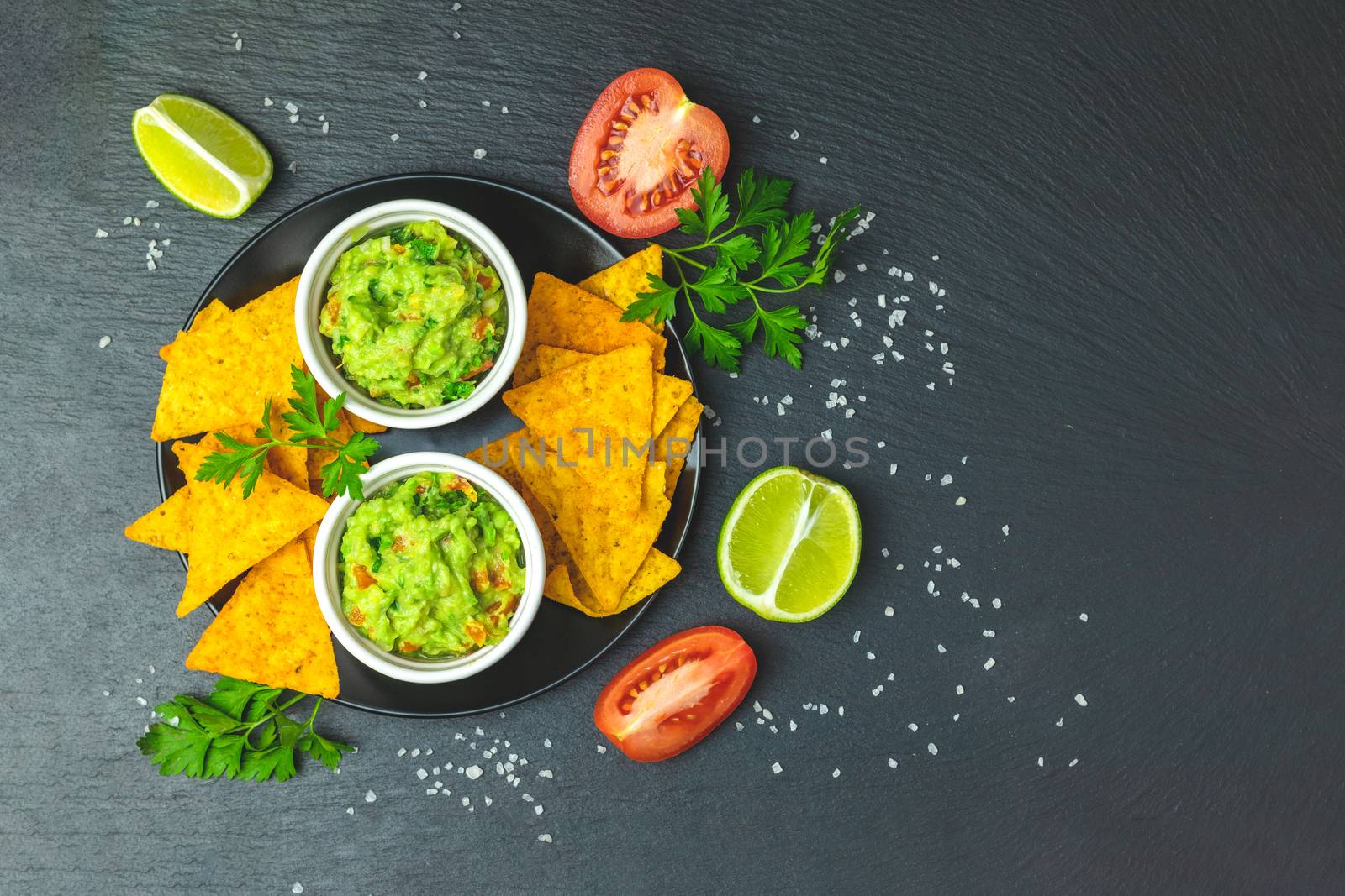 Guacamole and nachos with ingredients on the background of a bla by ArtSvitlyna