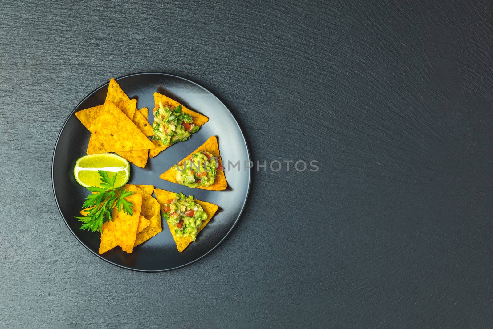 Guacamole and nachos with ingredients on the background of a bla by ArtSvitlyna