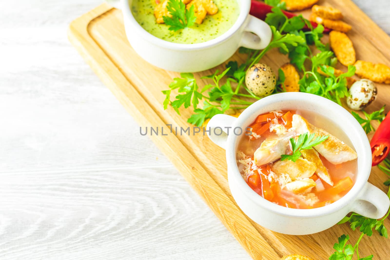 Concept of healthy vegetable and legume soups. Vegetables soup with carrot, eggs and chicken, mushroom cream soup with herbs and crackers and ingredients. Background of a light gray board, copy space