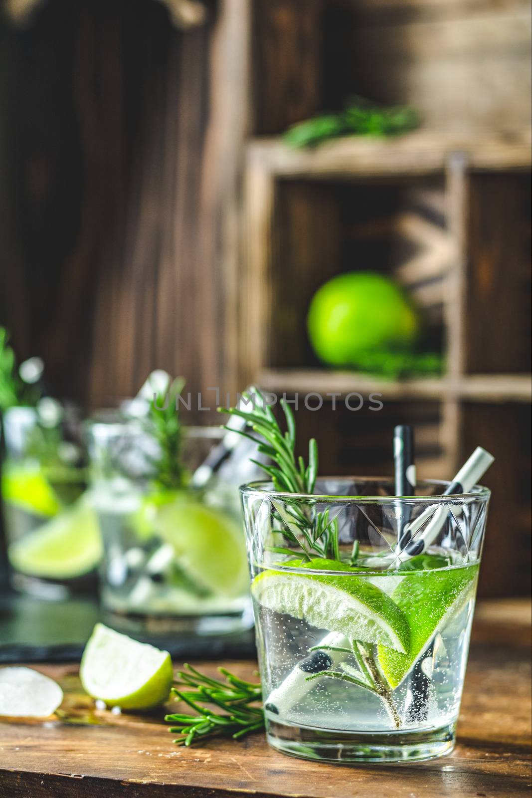 Fresh cocktail with lime, ice and rosemary, mojito cocktail in a bur on a rustic table, selective focus, shallow depth of the field.