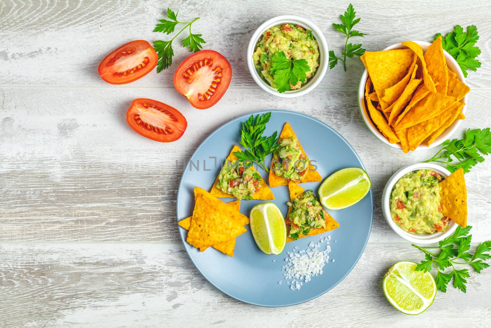 Guacamole and nachos with ingredients on the background of a lig by ArtSvitlyna
