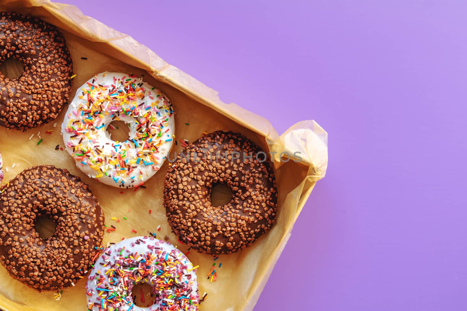 Delicious glazed donuts in box on violet surface by ArtSvitlyna