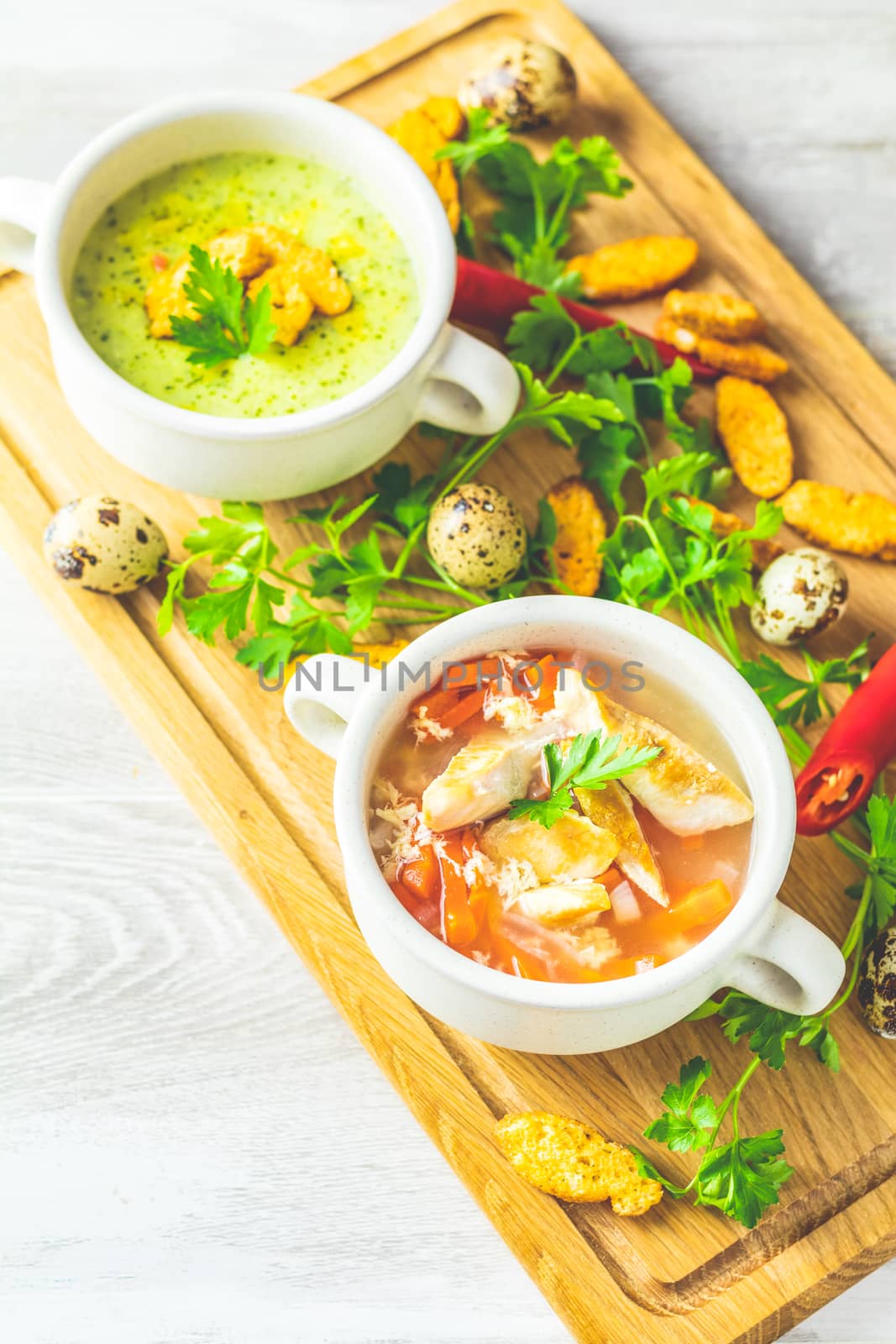 Concept of healthy vegetable and legume soups. Vegetables soup with carrot, eggs and chicken, mushroom cream soup with herbs and crackers and ingredients. Top view on the background of a light gray wooden board, copy space.