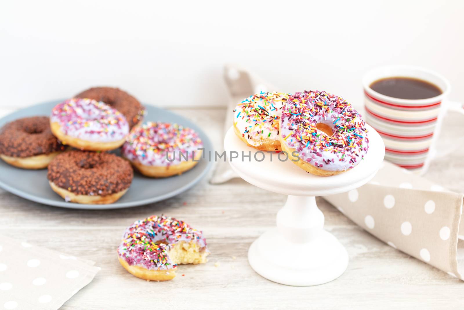 Delicious glazed donuts and cup of coffee on light wooden backgr by ArtSvitlyna