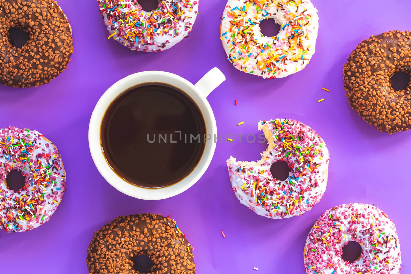 Delicious glazed donuts and cup of coffee on violet surface by ArtSvitlyna