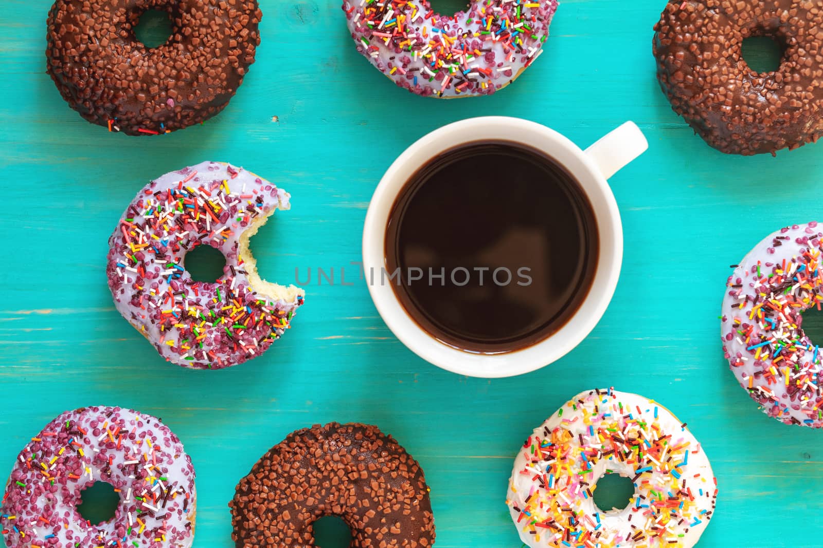 Delicious glazed donuts and cup of coffee on turquoise surface by ArtSvitlyna