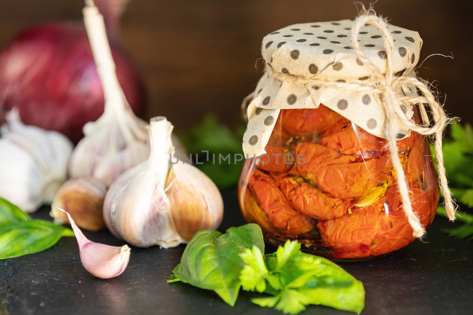 Sun dried tomatoes in glass jar on wooden background by ArtSvitlyna