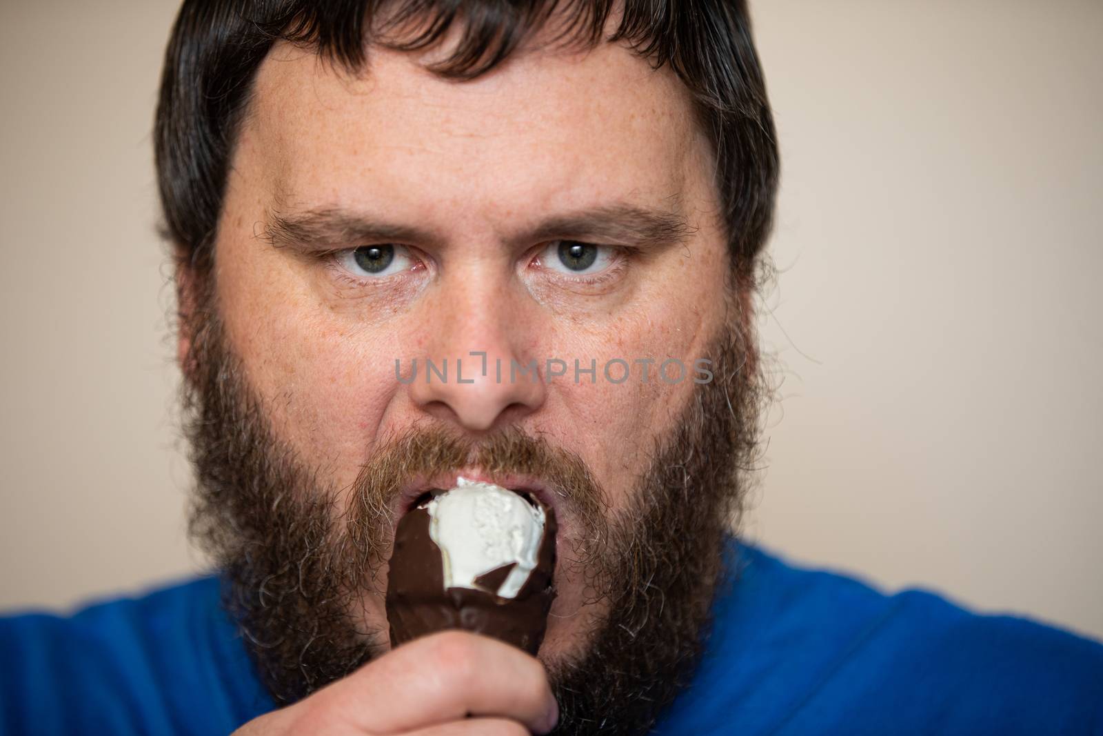 Bearded man eating ice cream with a firm look on his face