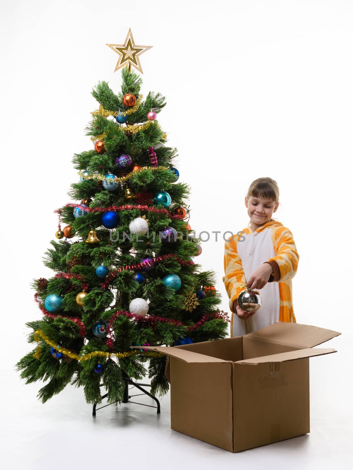 Girl examines Christmas decorations pulling them out of the Christmas tree