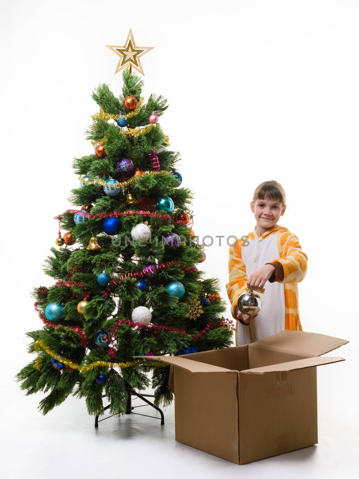 Girl removes Christmas balls from the Christmas tree and puts in a box