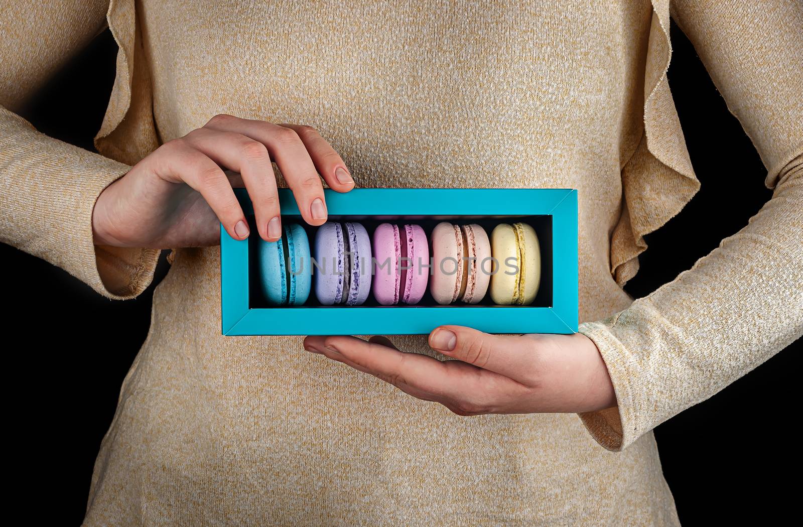 Beautiful female hands hold multicolored macaroons in gift box