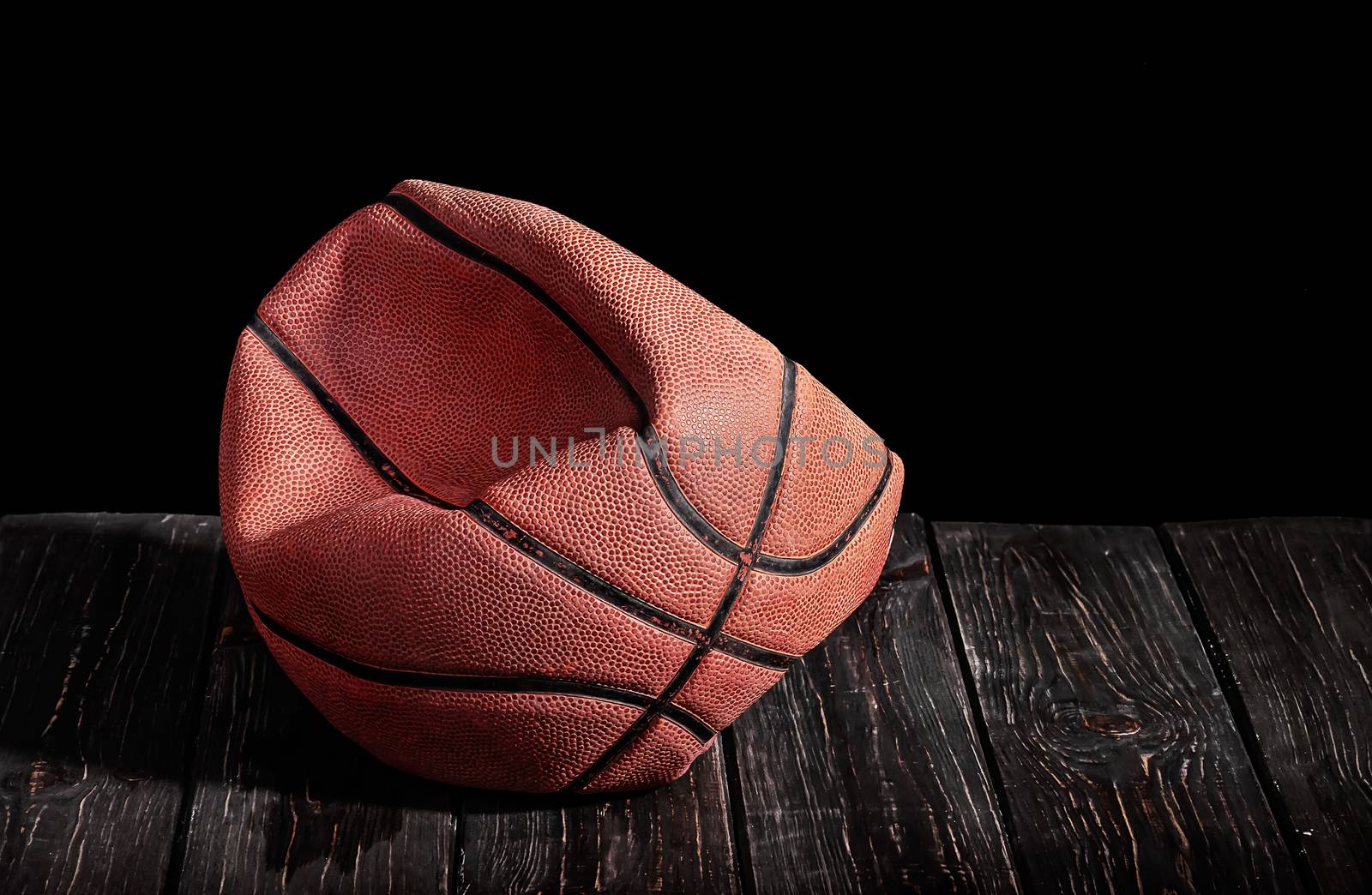 Deflated and rumpled old ball on a wooden floor by Cipariss