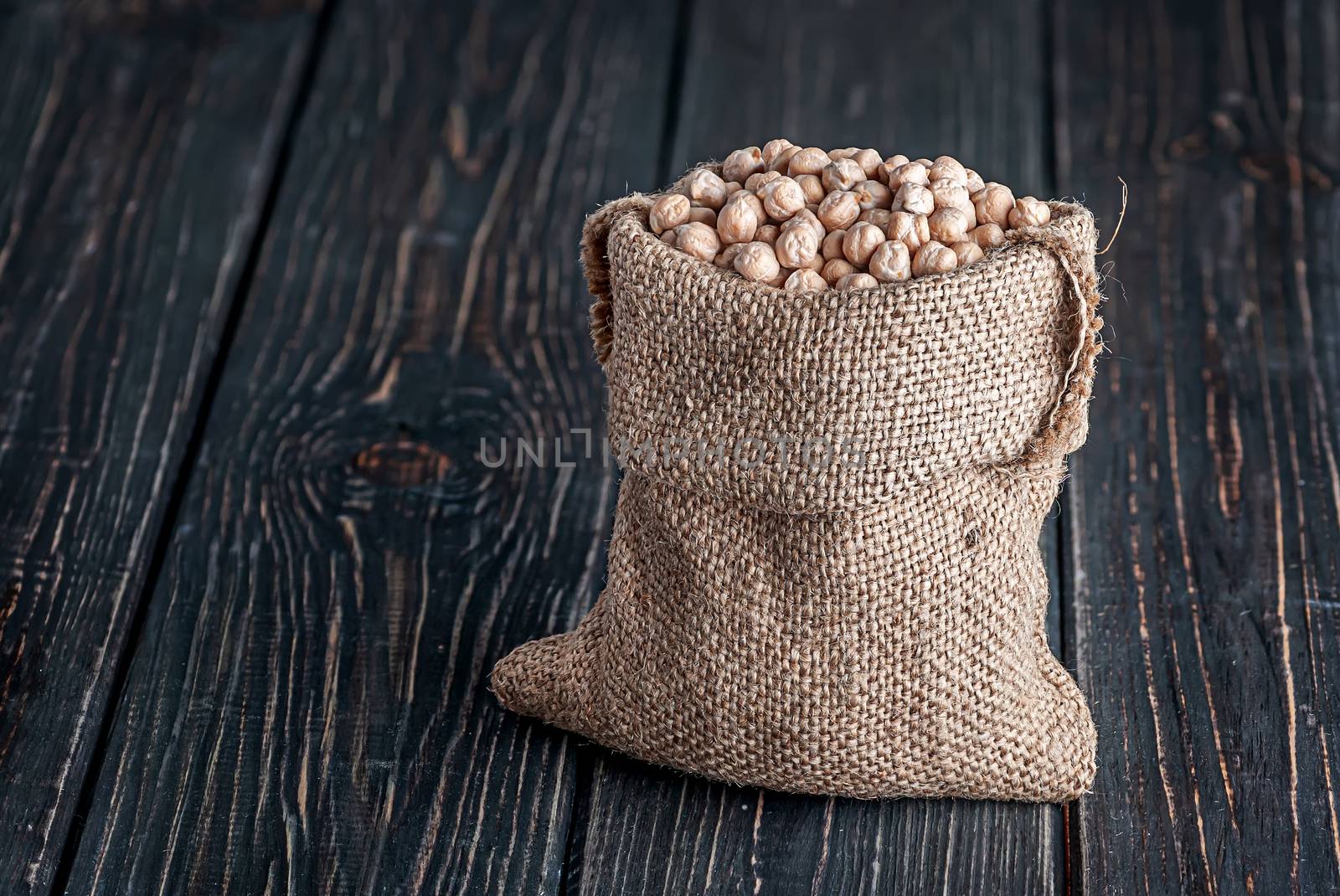 Sack of chickpeas stands on wooden background