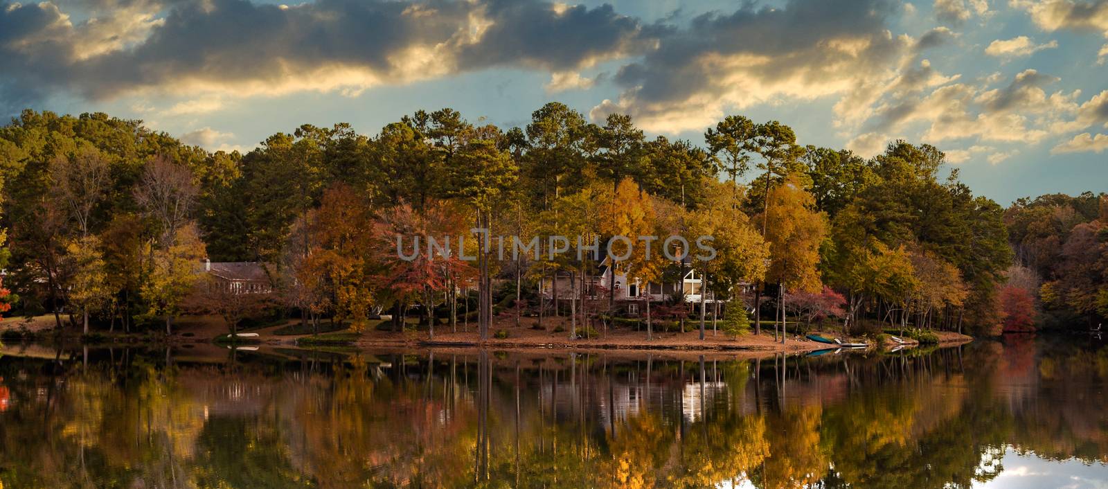 House among trees on the shore of a calm lake in Autumn