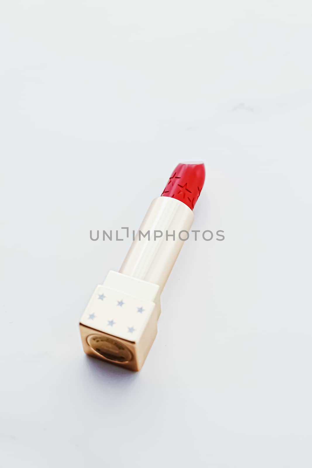 Luxury lipstick in a golden tube on white marble background, make-up and cosmetics concept