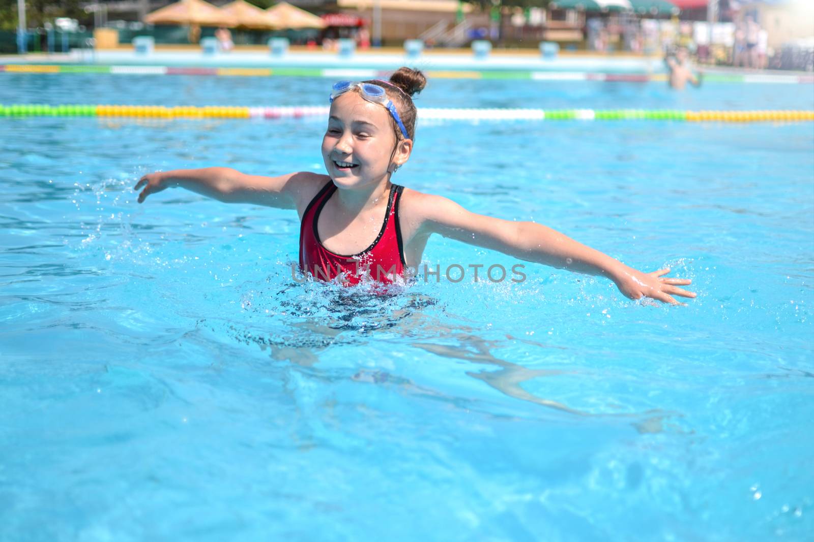 Young girl splashing in the pool on a sunny day