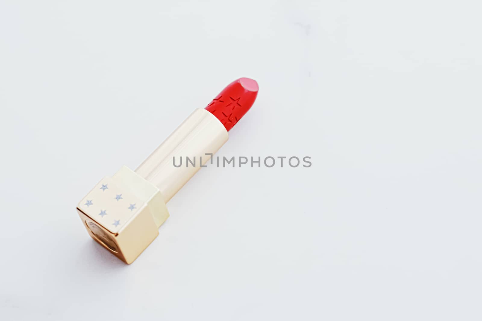 Luxury lipstick in a golden tube on white marble background, make-up and cosmetics concept