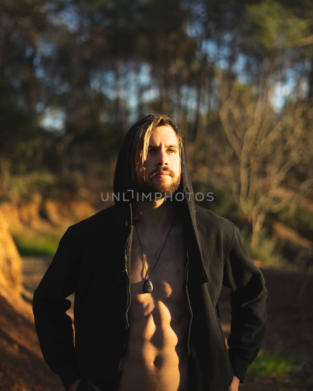 Portrait of young bearded man with beautiful sunlight, he is hooded