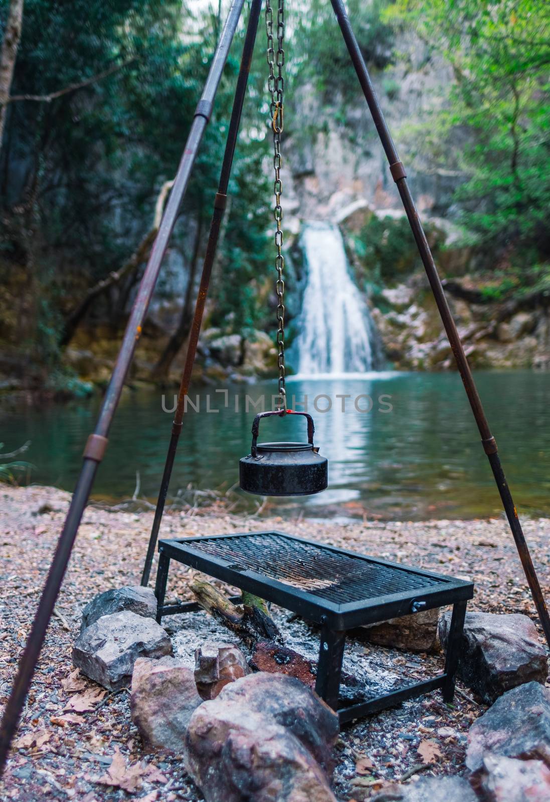 Vintage black teapot hanging over campfire by waterfall in Eksili, Antalya, Turkey.