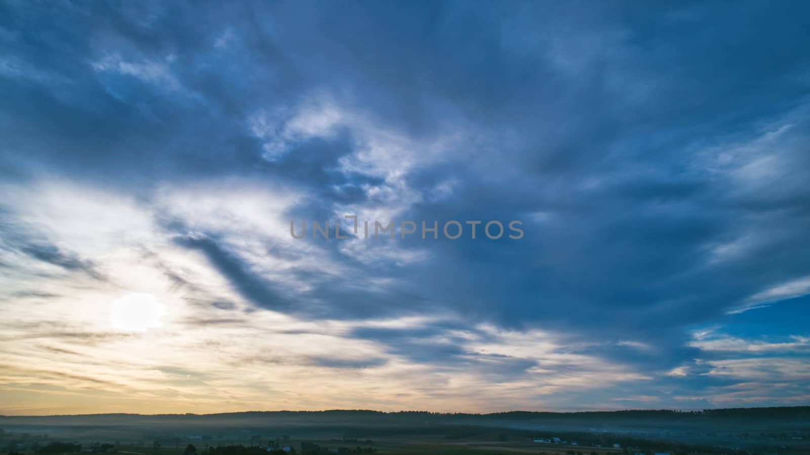 Aerial View of a Late Afternoon Sun With Partly Cloudy Blue Sky Over Farm Countryside Background