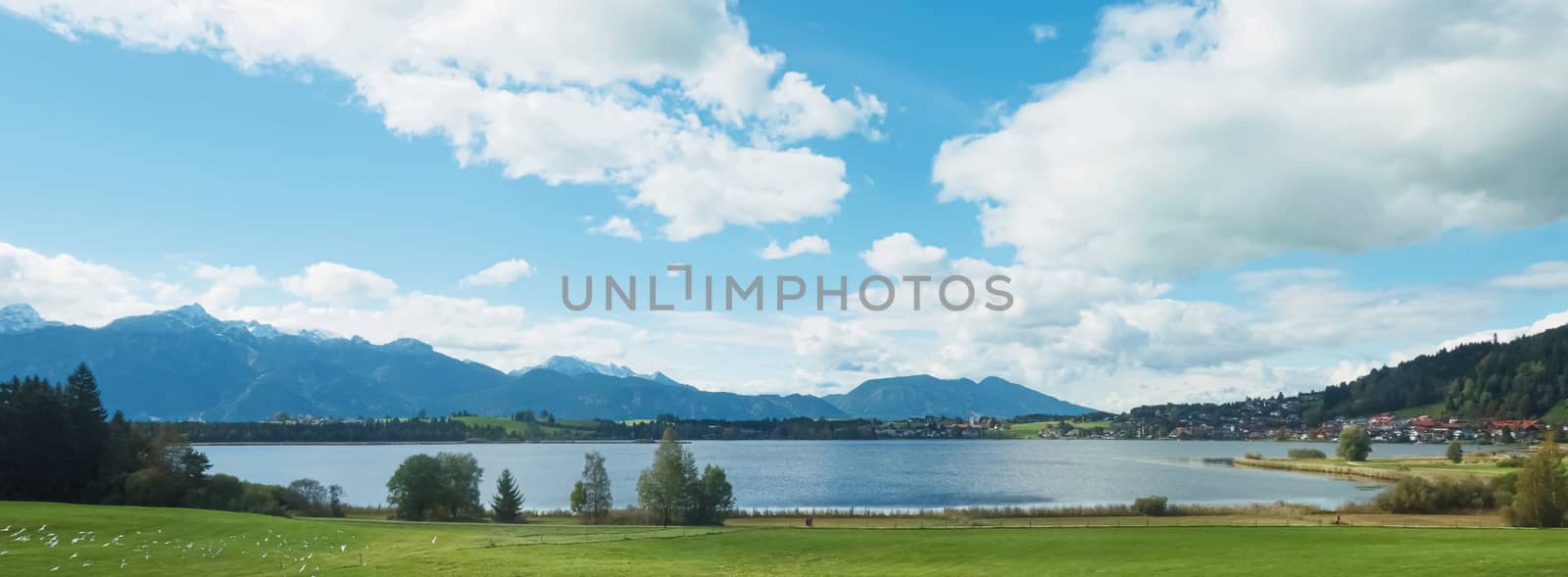 Beautiful nature of European Alps, landscape view of alpine mountains, lake and village on a sunny day, travel and destination scenery