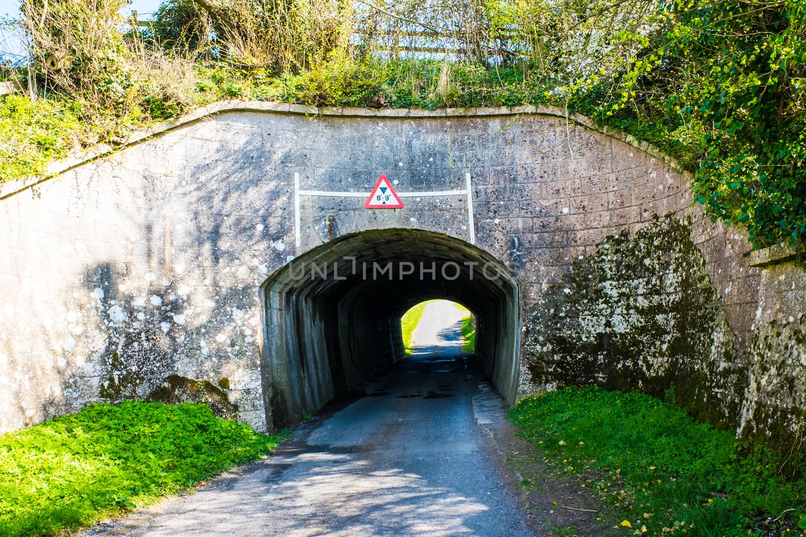 Old brick tunnel carrying narrow road under railway line