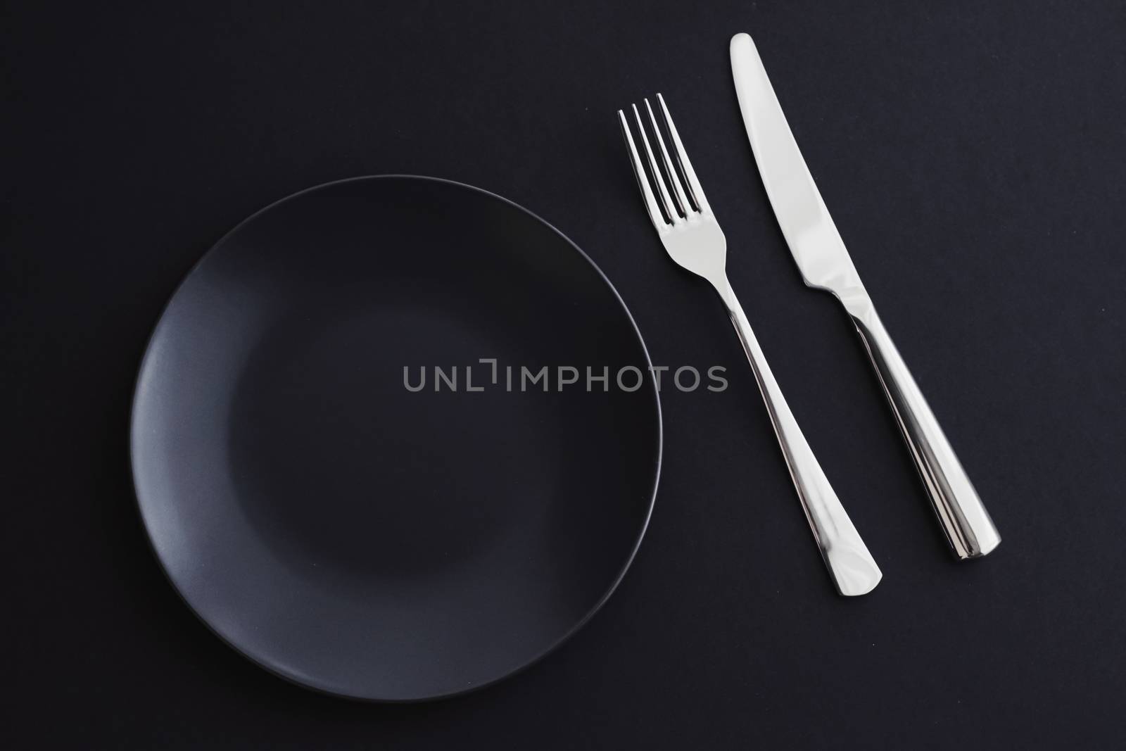 Empty plates and silverware on black background, premium tableware for holiday dinner, minimalistic design and diet concept