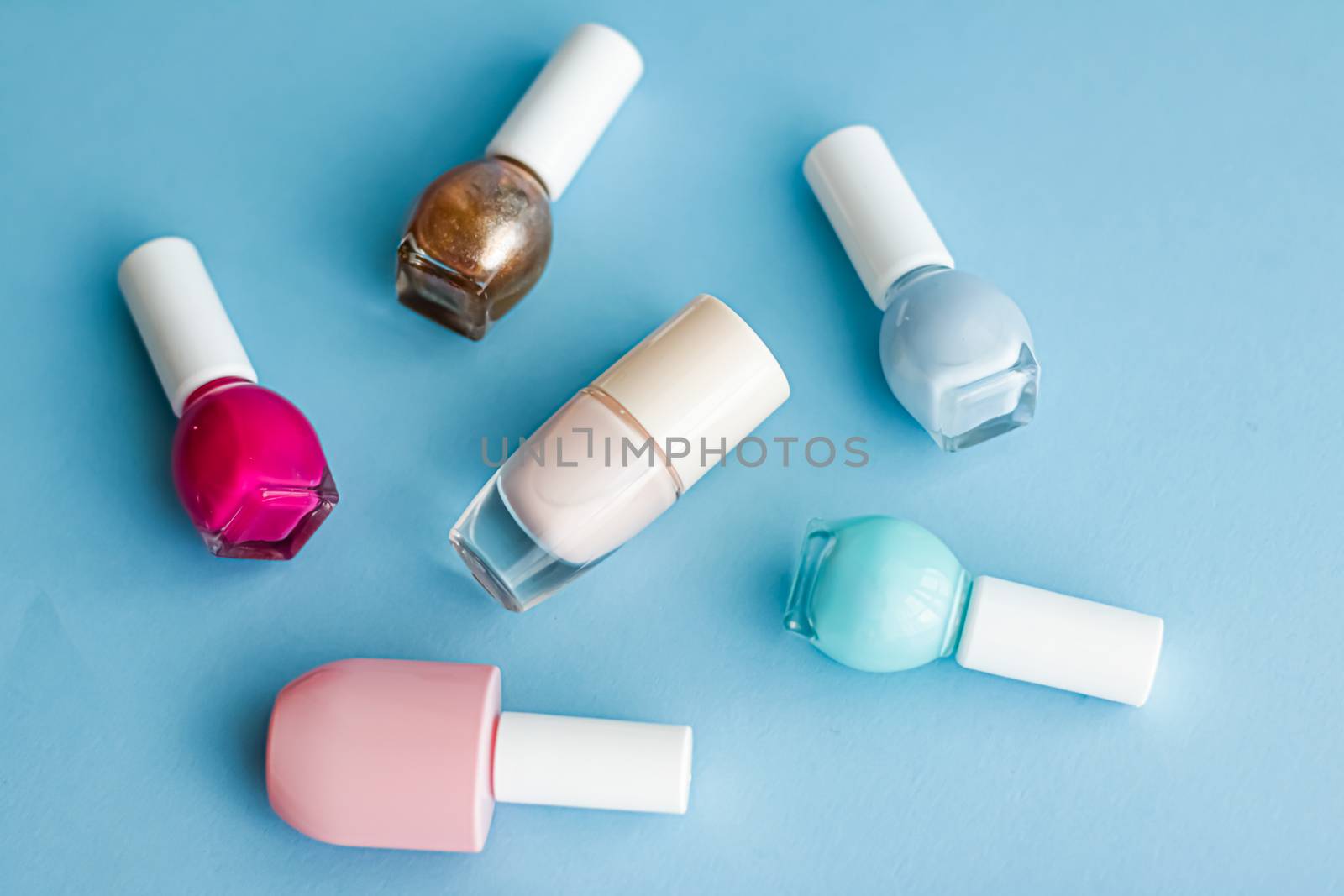 Colourful nail polish bottles on blue background, organic make-up and cosmetic products for beauty brand by Anneleven