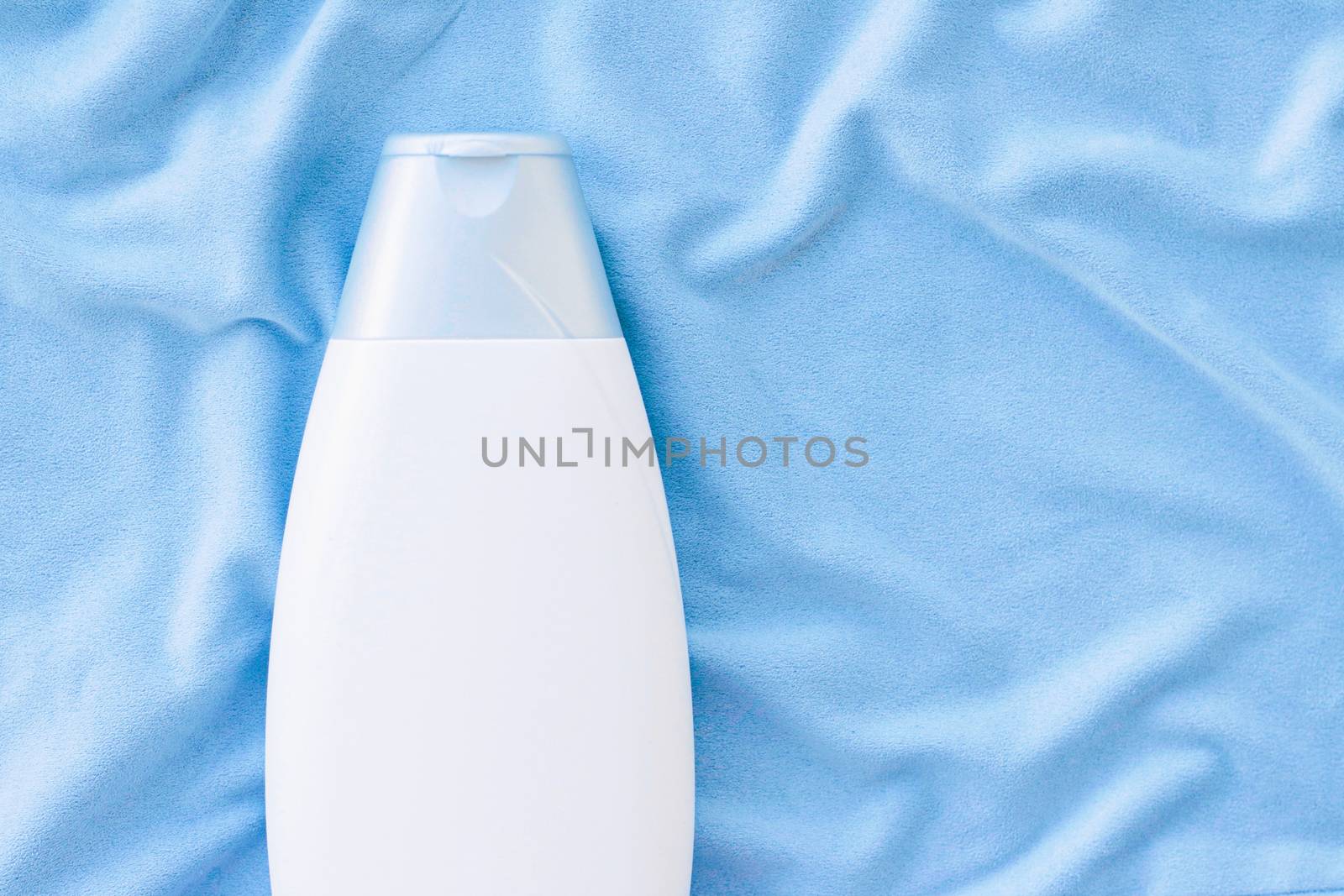 Blank label shampoo bottle or shower gel mockup on blue silk background, beauty product and body care cosmetics, flatlay