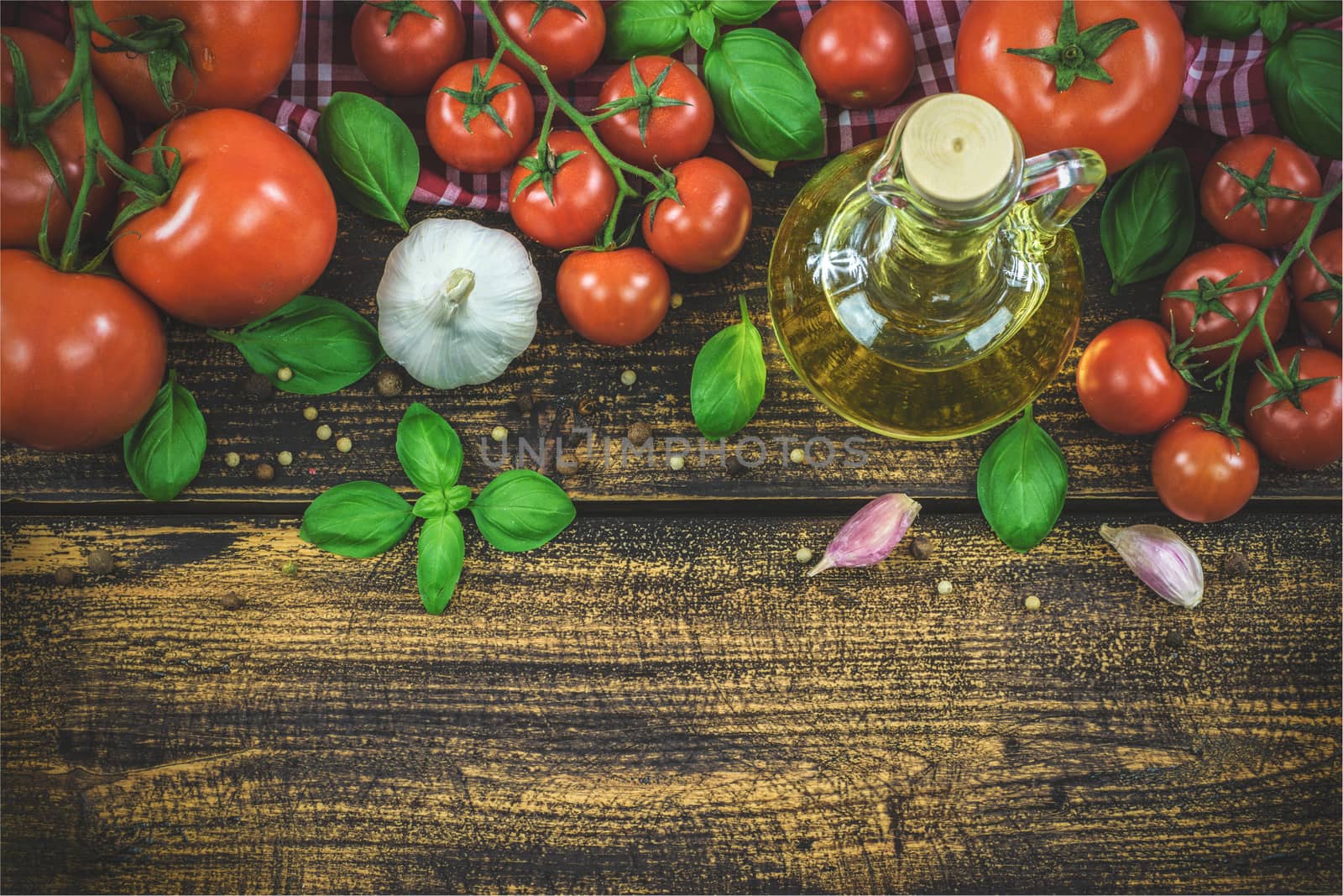 Overhead shot of the classic ingredients of Italian cuisine: basil, garlic, olive oil, pepper on a wooden vintage table (reducet tone)