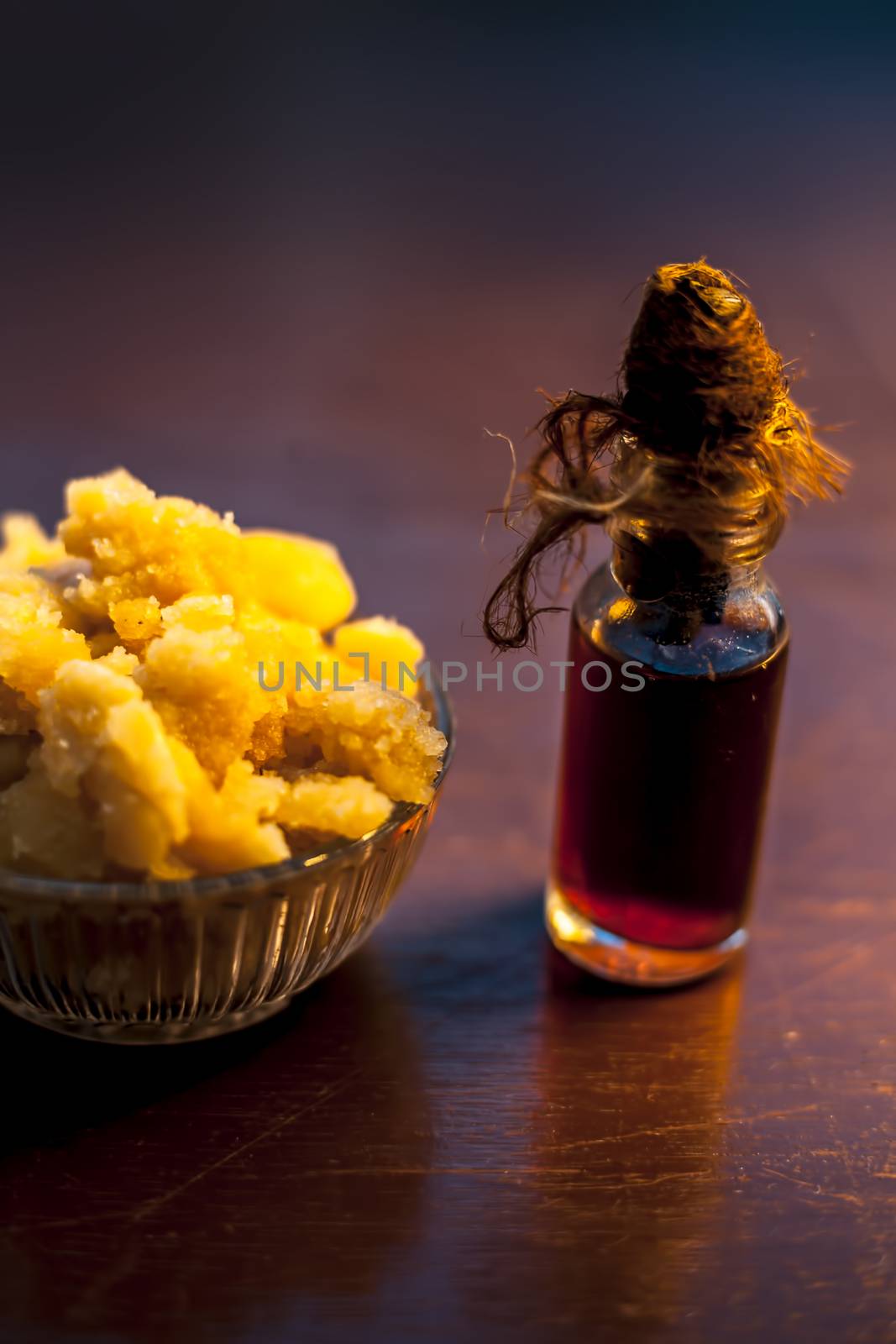 Close up of glass cup full of raw jaggery or gud or palm jaggery and its extracted oil in a glass bottle used for oil pulling in ayurvedic dental treatment. Vertical shot. by mirzamlk