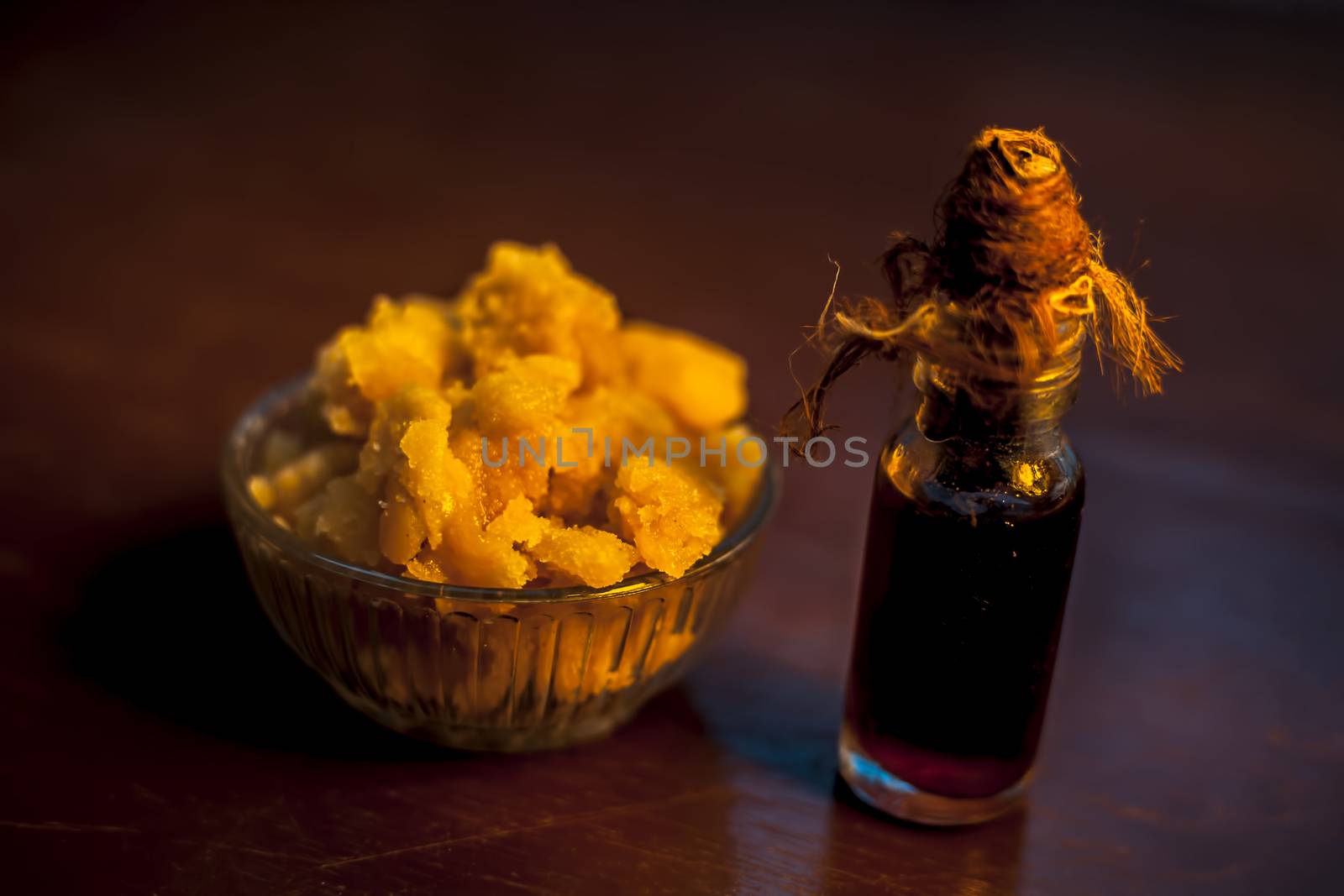 Close up of glass cup full of raw jaggery or gud or palm jaggery and its extracted oil in a glass bottle used for oil pulling in ayurvedic dental treatment. Horizontal shot.