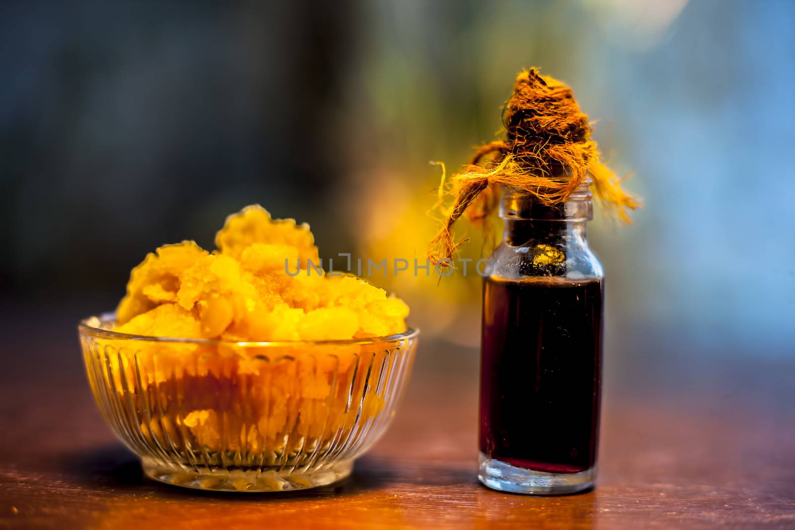 Close up of glass cup full of raw jaggery or gud or palm jaggery and its extracted oil in a glass bottle used for oil pulling in ayurvedic dental treatment. Horizontal shot. by mirzamlk
