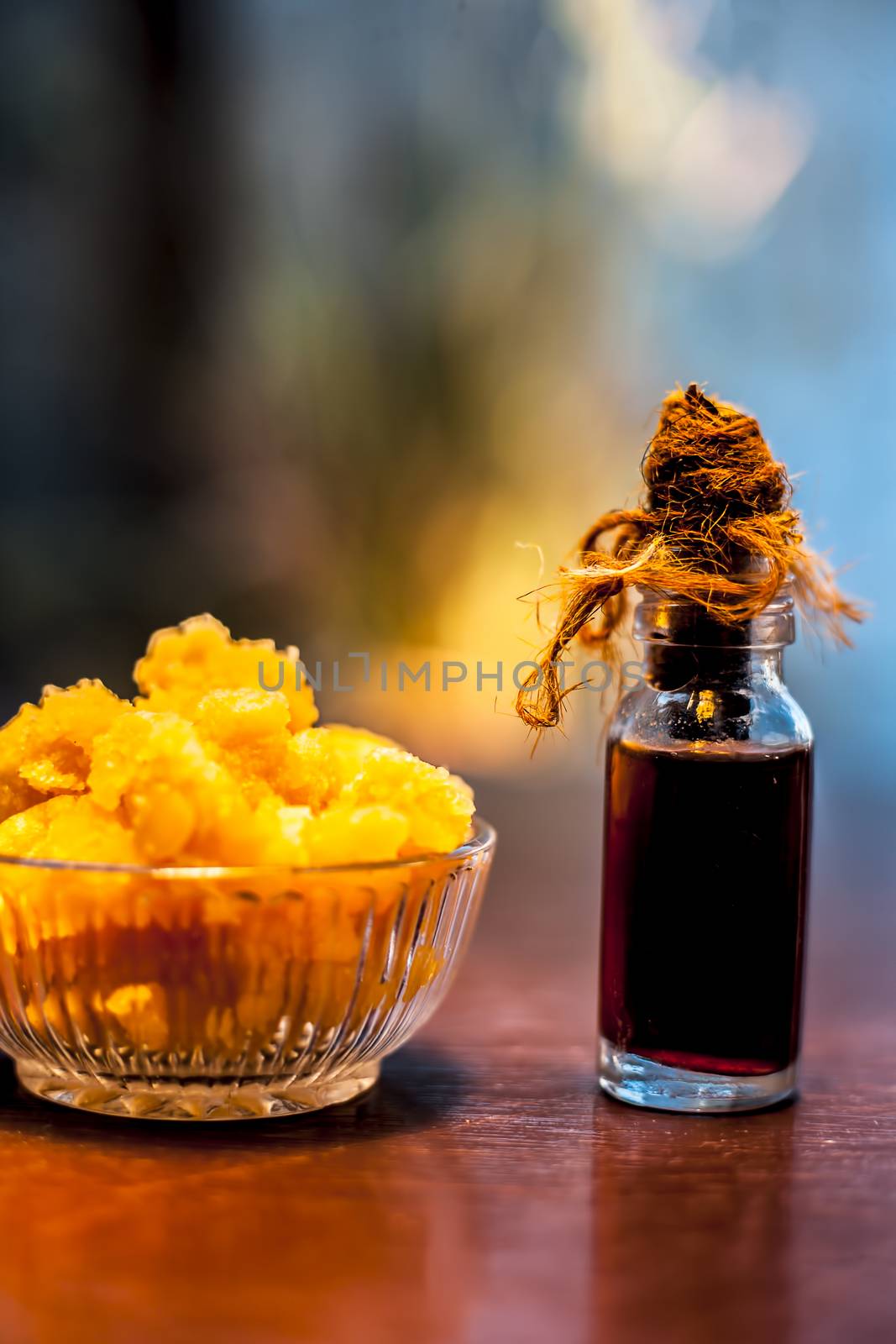 Close up of glass cup full of raw jaggery or gud or palm jaggery and its extracted oil in a glass bottle used for oil pulling in ayurvedic dental treatment. Vertical shot.