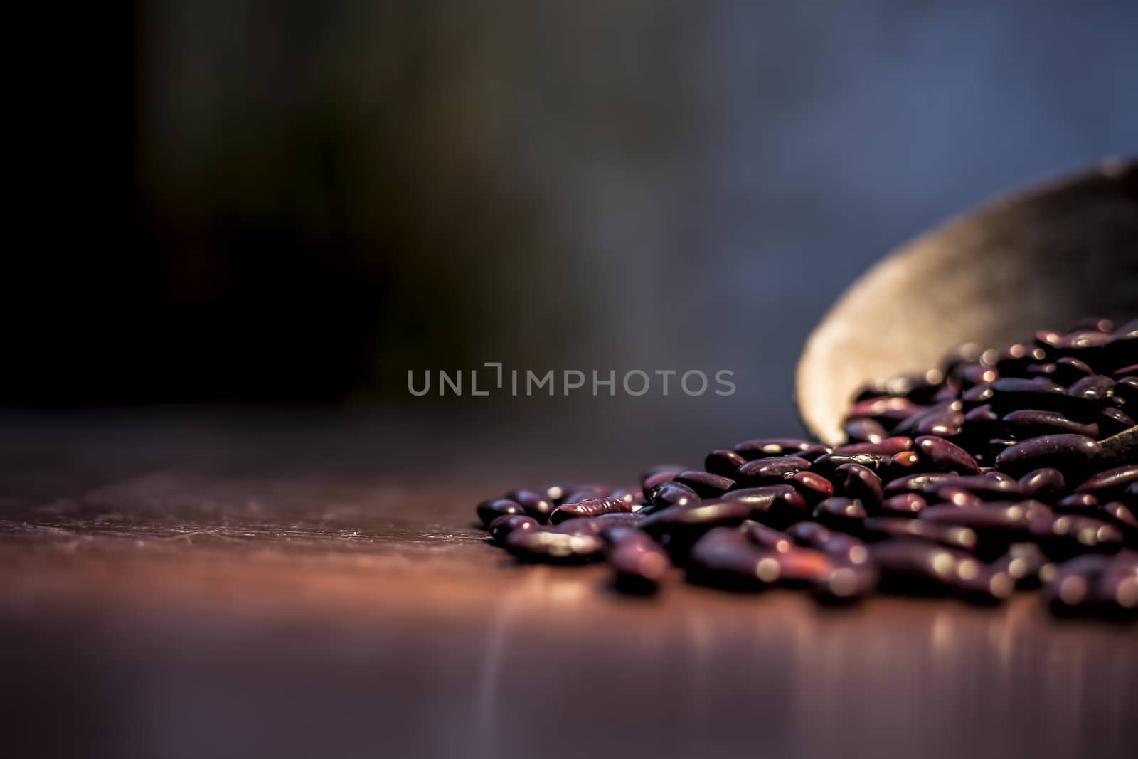 Close up of raw kidney beans on brown colored surface in a clay bowl with a spotlight on it. Horizontal shot.