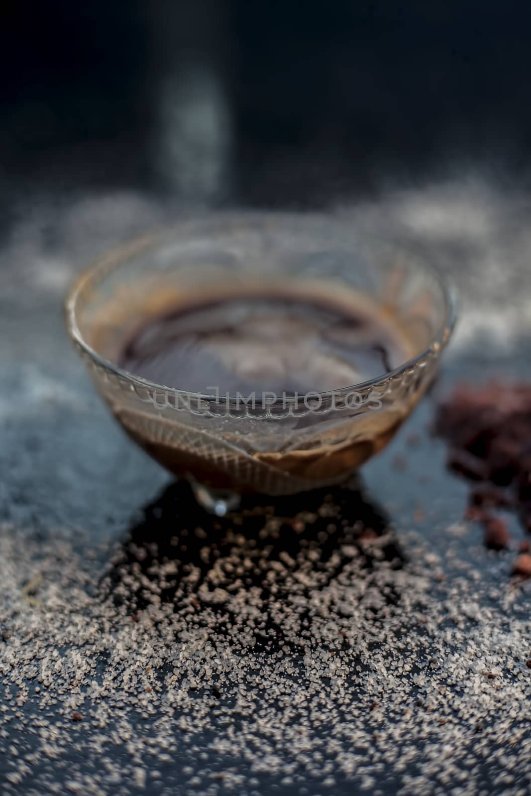 Close up shot of a bowl of the salt face mask of rock salt or sendha namak in it along with some crystals spread on the surface. Vertical shot. by mirzamlk