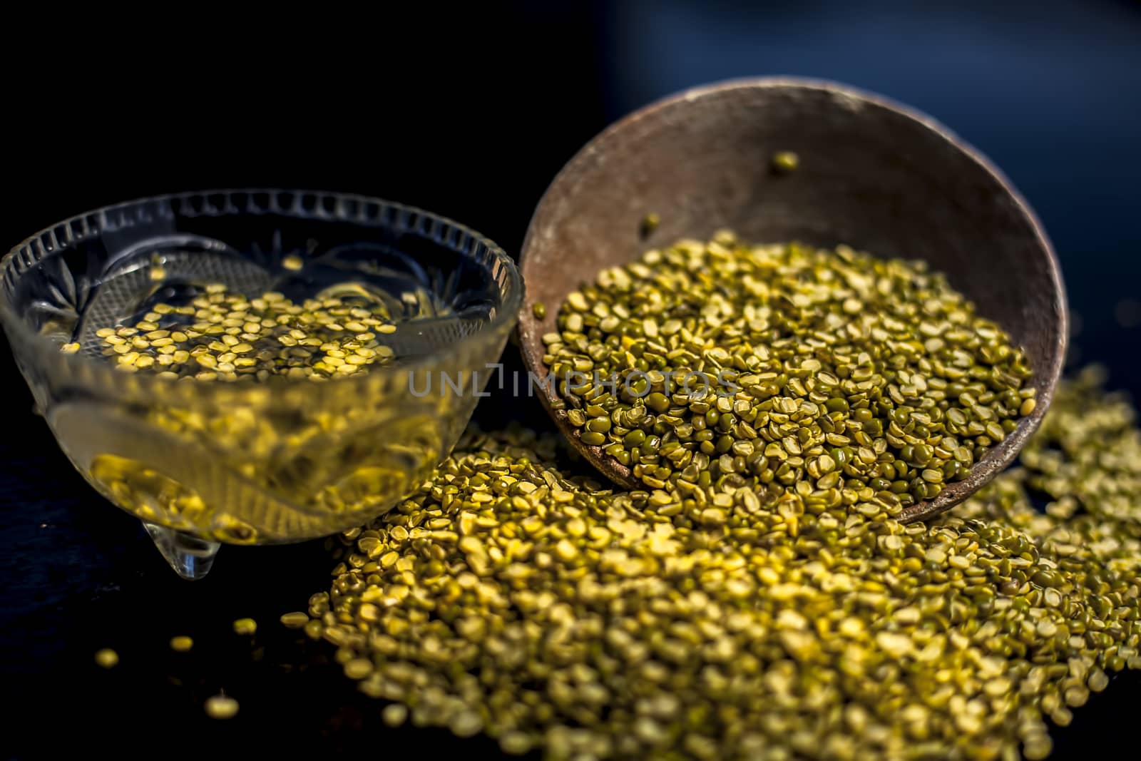 Close shot of mung bean or moong dal in a clay bowl along with some water and moong dal well mixed on a black glossy surface. Horizontal shot with Rembrandt lighting technique. by mirzamlk
