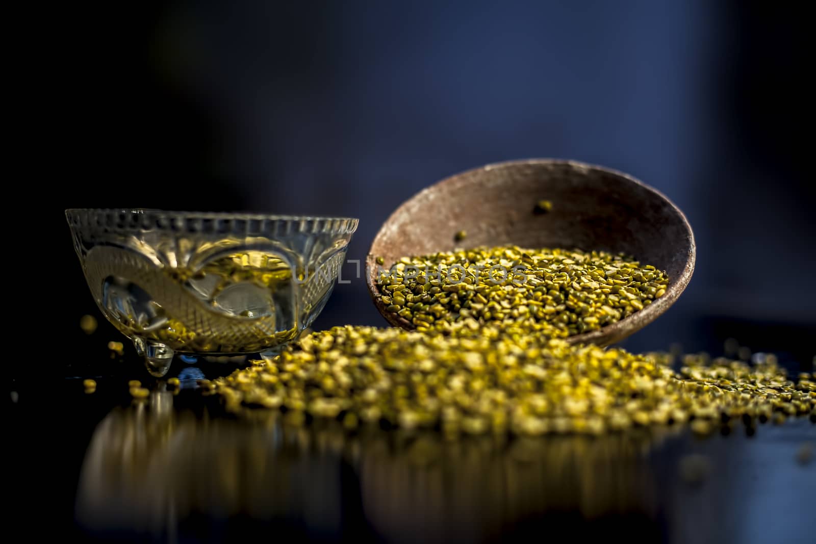 Close shot of mung bean or moong dal in a clay bowl along with some water and moong dal well mixed on a black glossy surface. Horizontal shot with Rembrandt lighting technique. by mirzamlk