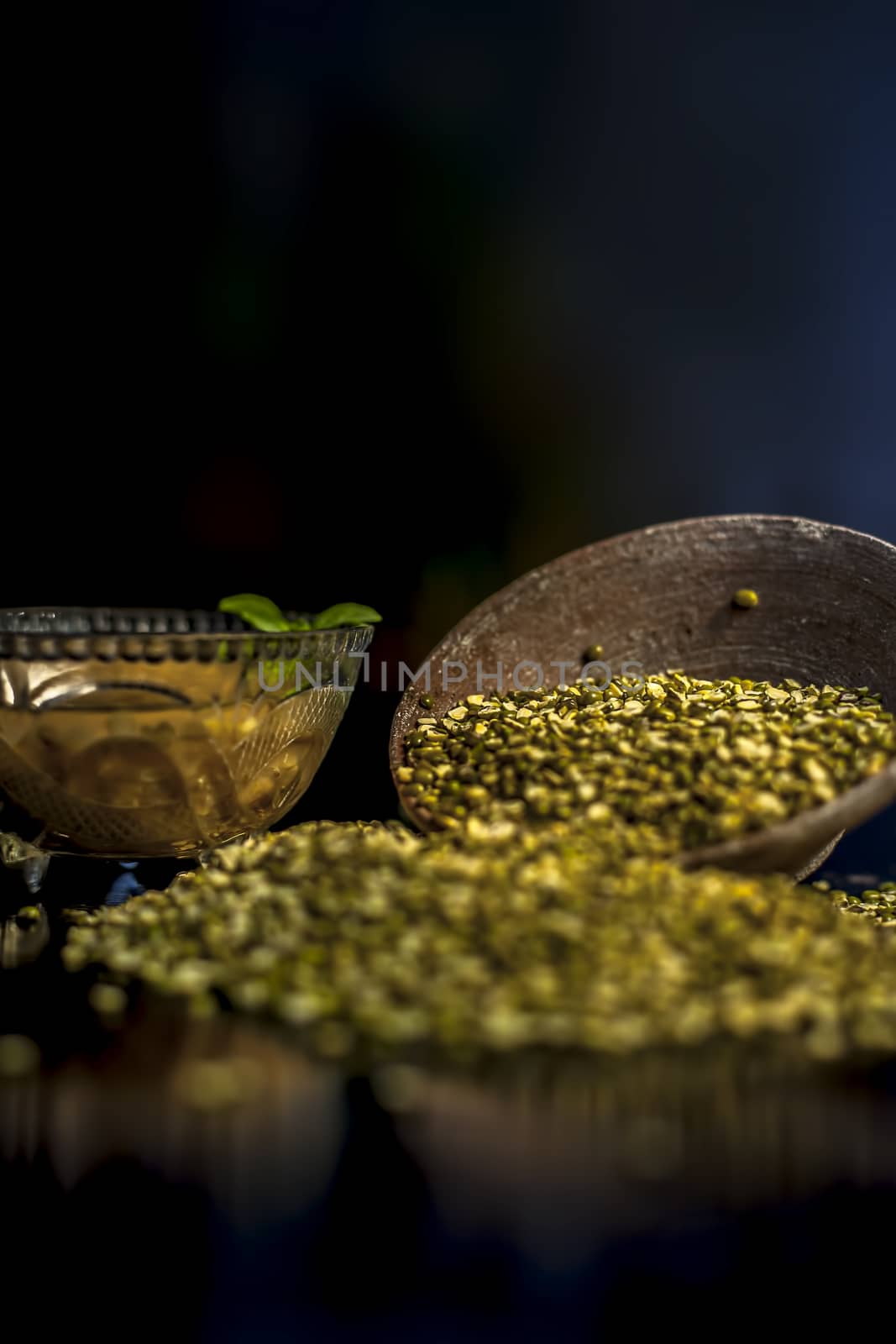 Close shot of mung bean or moong dal in a clay bowl along with some water and moong dal well mixed on a black glossy surface. Horizontal shot with Rembrandt lighting technique. by mirzamlk