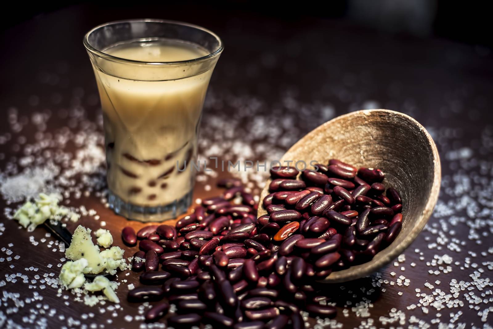 Red bean bubble tea in a glass along with some raw kidney beans, butter and sugar on the brown surface with Rembrandt light technique. Horizontal shot. by mirzamlk