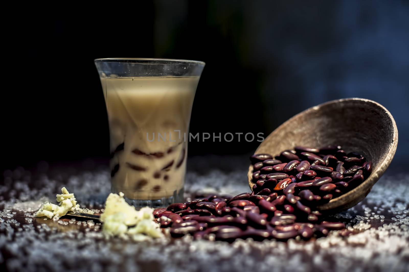 Red bean bubble tea in a glass along with some raw kidney beans, butter and sugar on the brown surface with Rembrandt light technique. Horizontal shot.