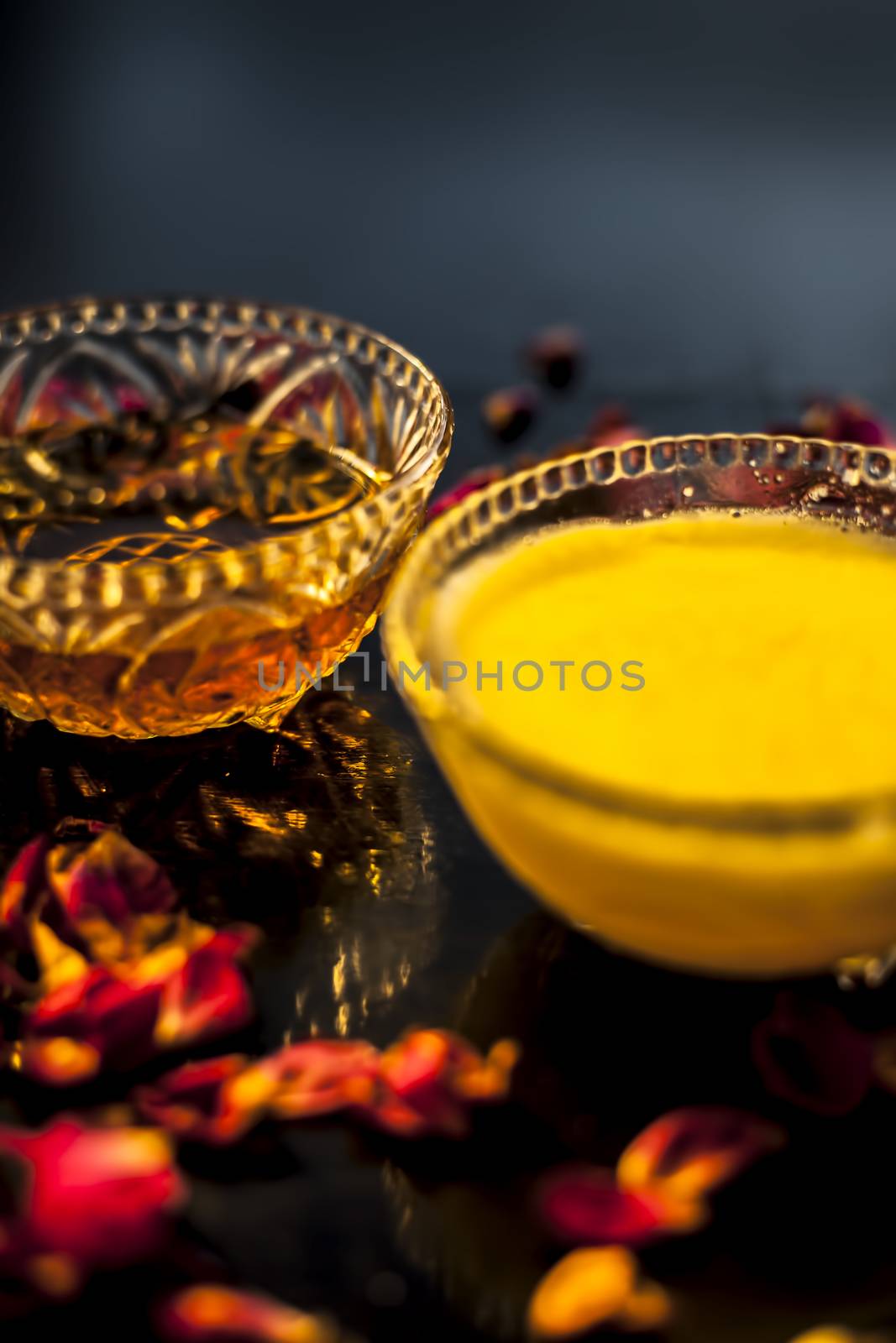 Ayurvedic moisturizer face mask on black glossy surface in a glass bowl with some ghee or clarified butter, honey and pack.