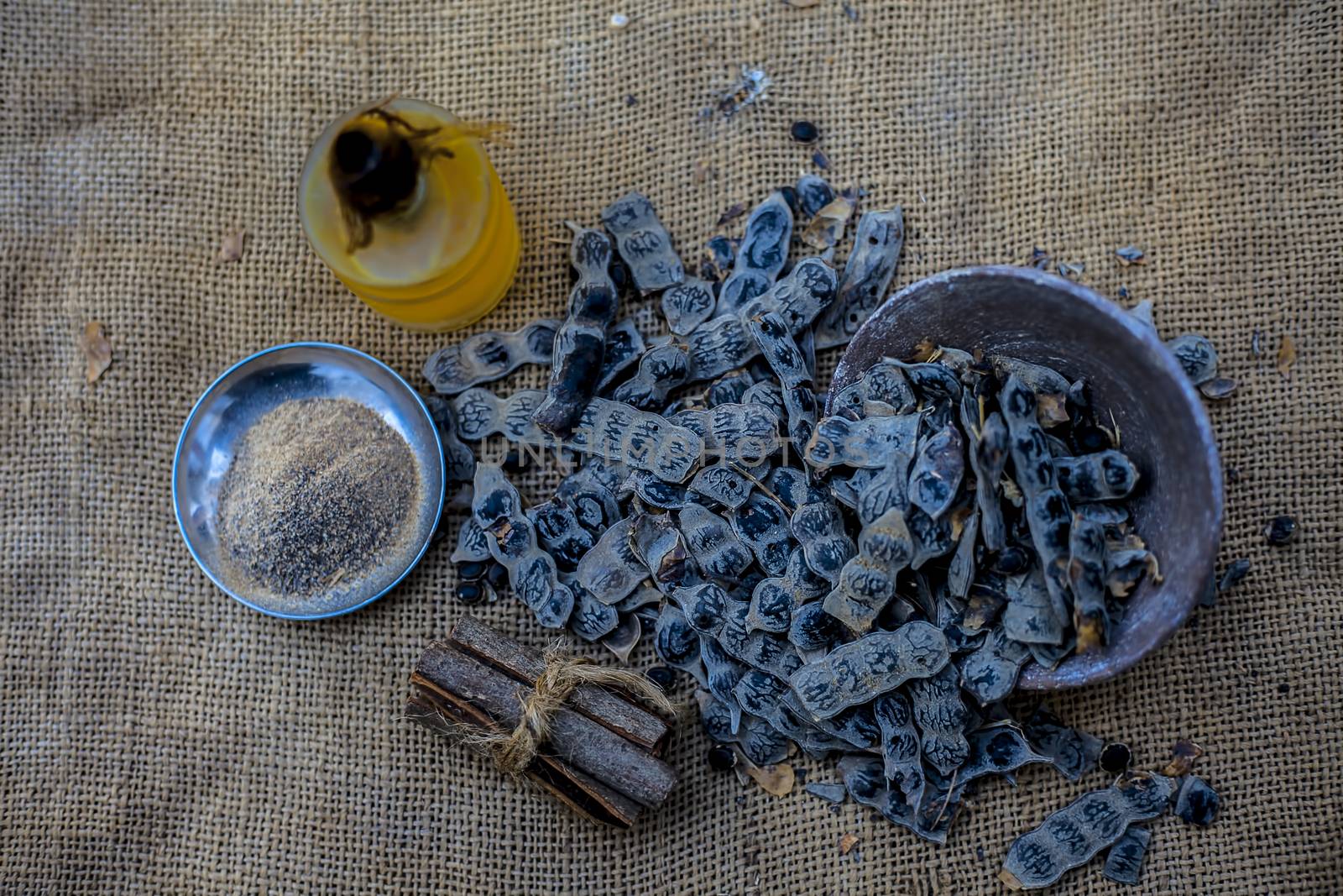 Ingredients for ayurvedic babool toothpaste on gunny bag's surface which are cinnamon stick, essential oil, baking soda, and babool powder.