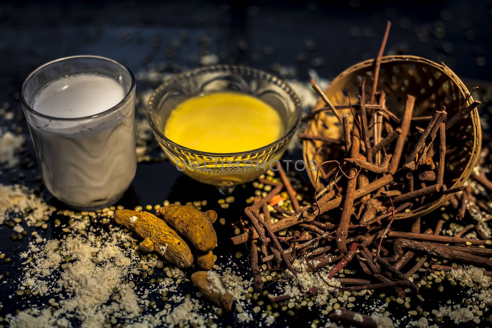 Ayurvedic blood purifier and skin glow face mask consisting of Manjistha, mung bean, haldi/turmeric, and milk. Horizontal shot of face mask with entire constituents with it on a black surface. by mirzamlk