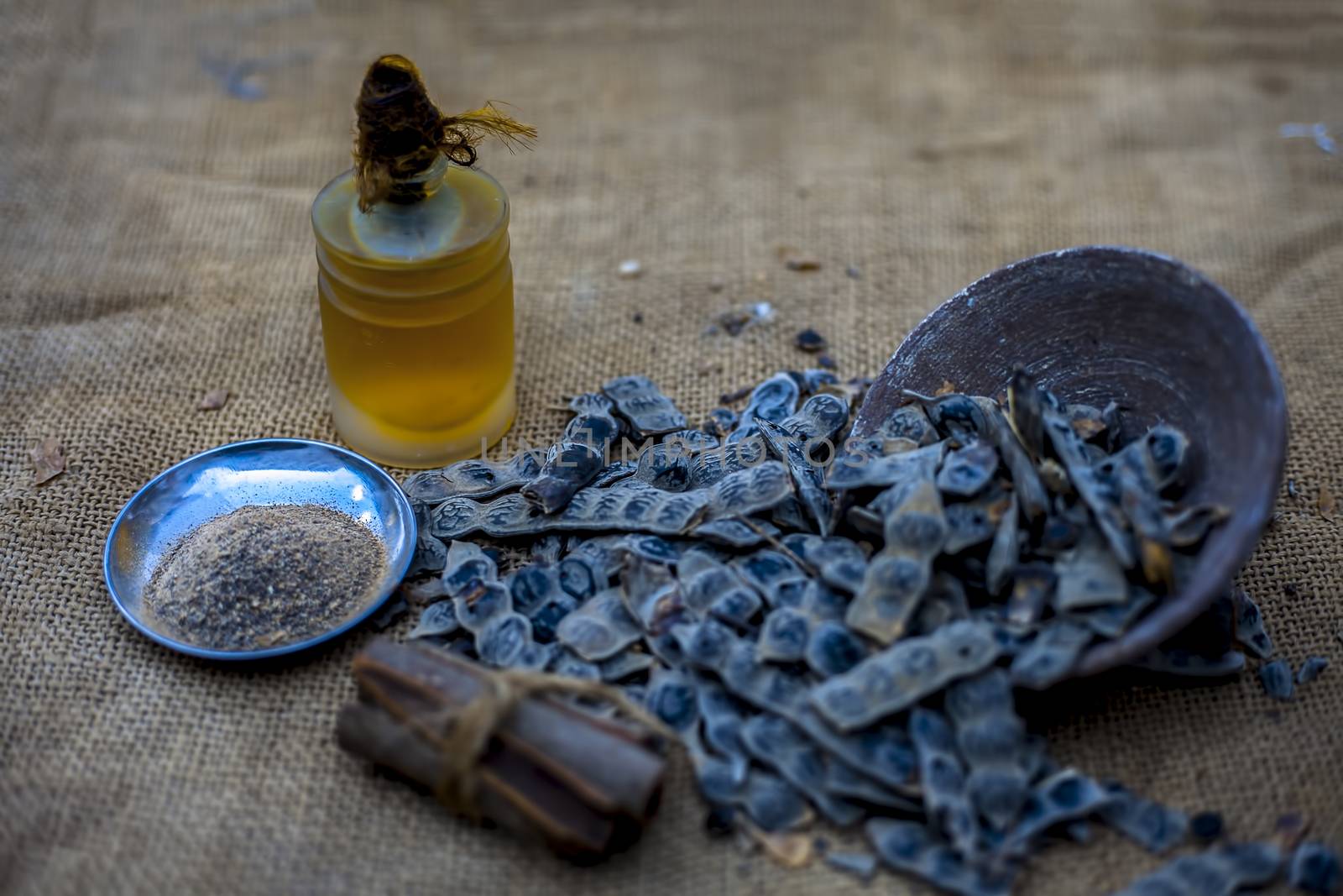 Ingredients for ayurvedic babool toothpaste on gunny bag's surface which are cinnamon stick, essential oil, baking soda, and babool powder.