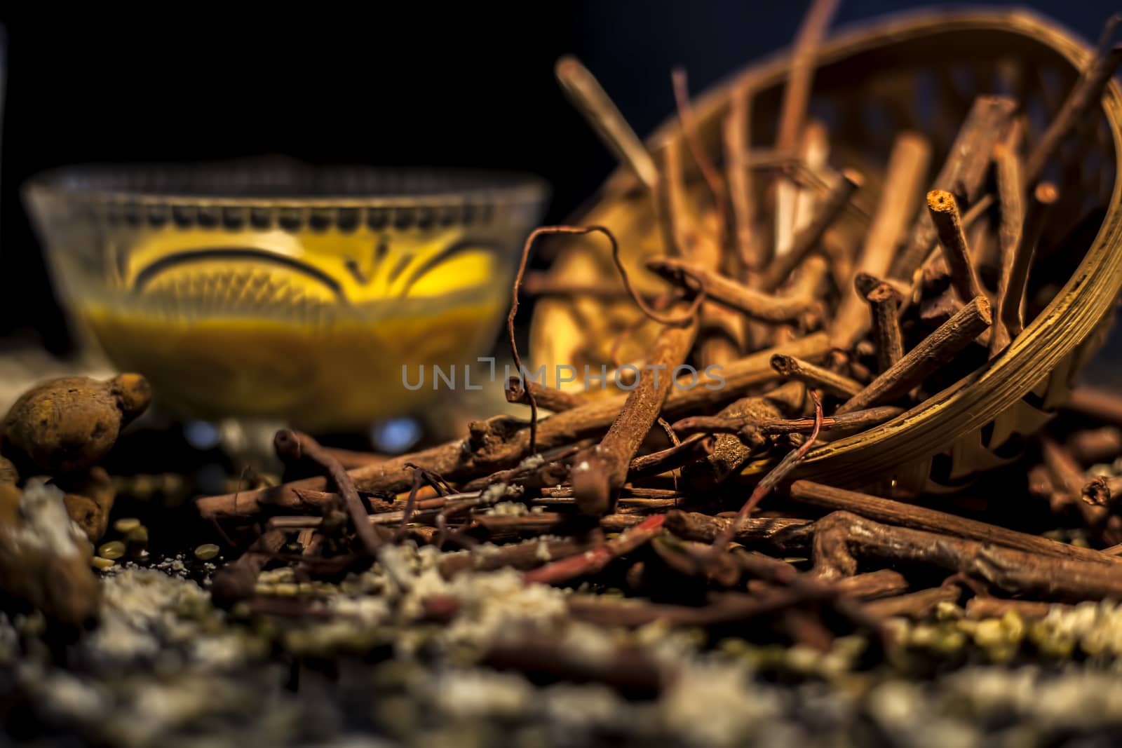 Close up shot of a bunch of manjistha herb roots in a container on a blue surface along with some other ingredients with it.