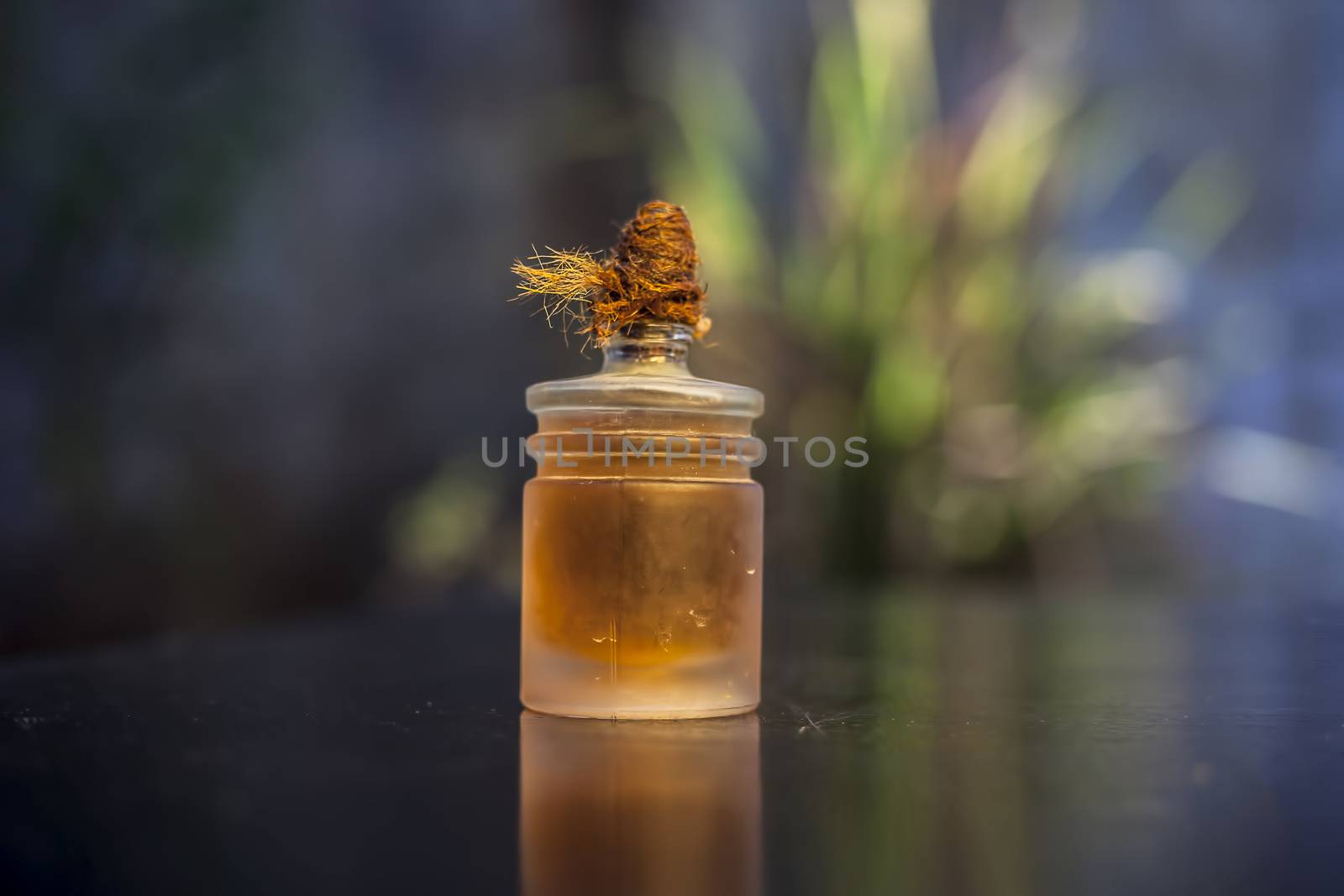 Brown colored essential oil-filled glass bottle on a wooden surface with creative lighting, selective focus and blurred background. by mirzamlk