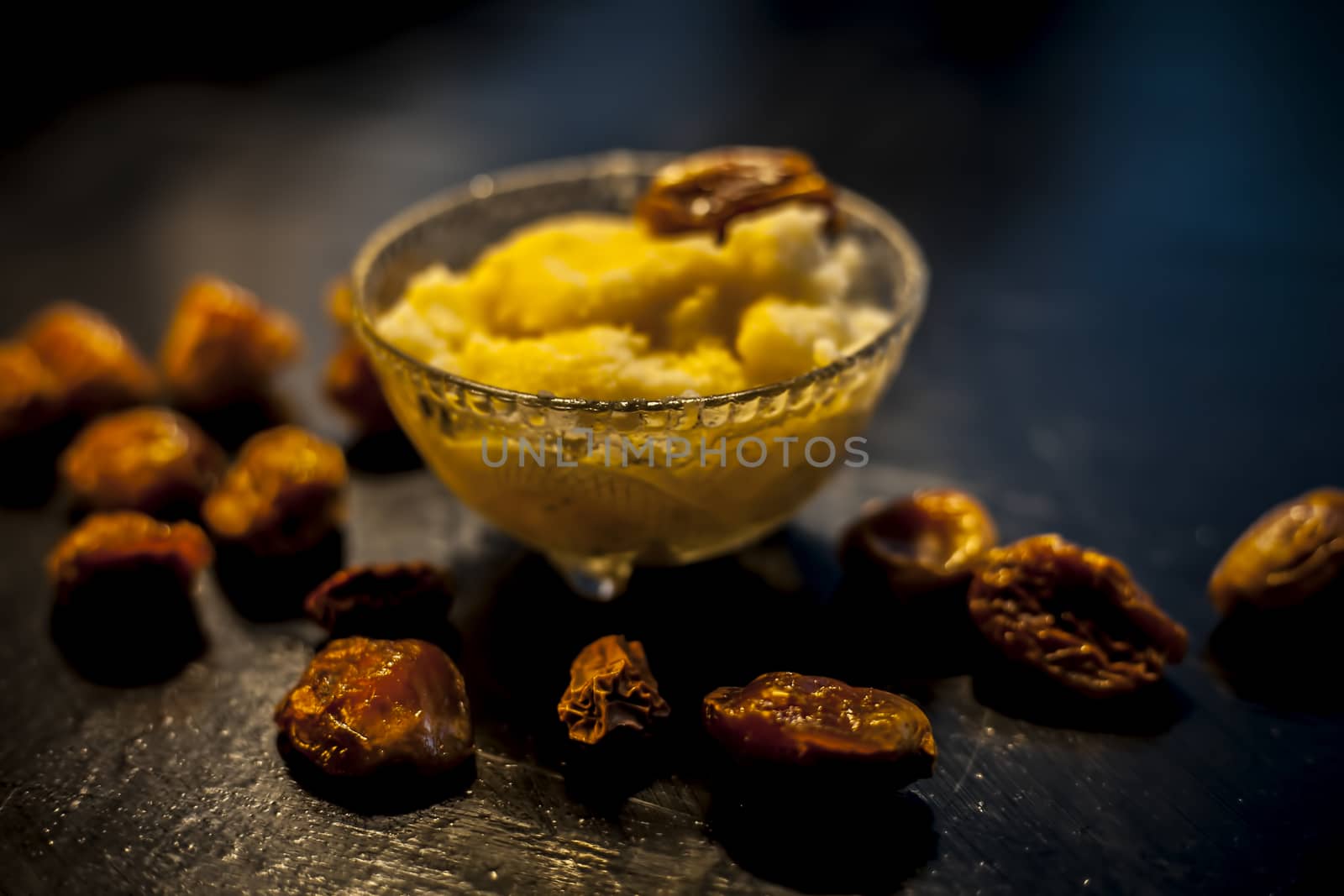 Close up shot of dates soaked in ghee for better stamina and health on black wooden surface along with ghee or clarified butter. Horizontal shot. by mirzamlk